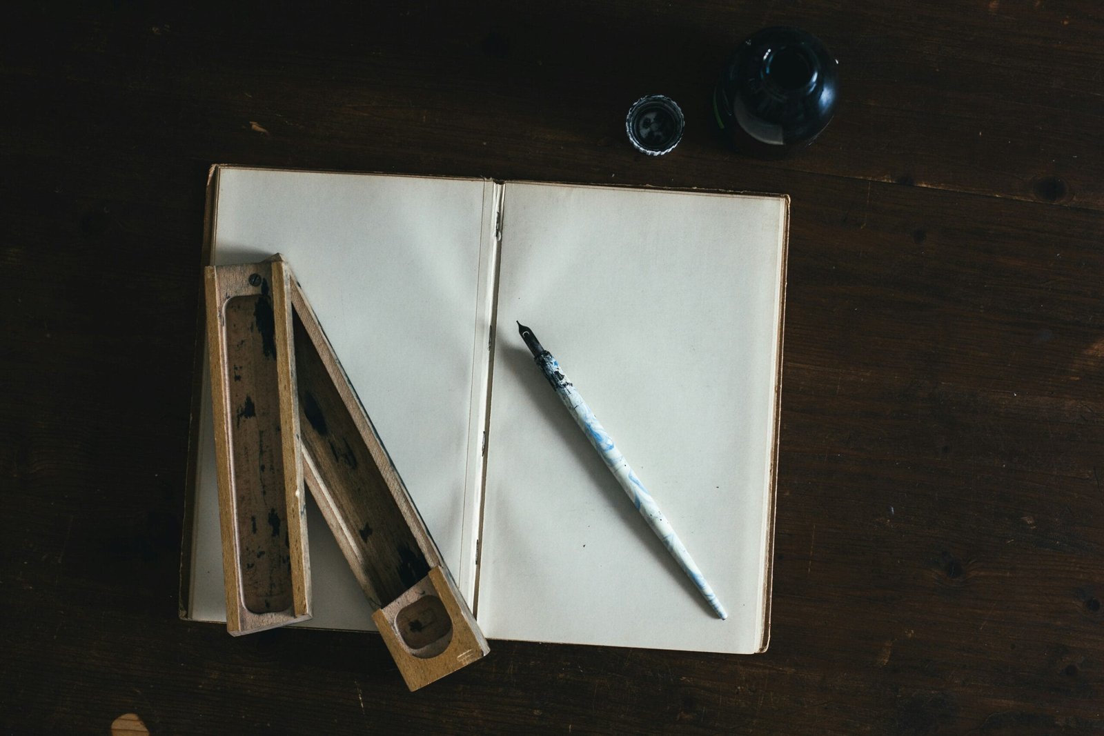 White fountain pen on an open book of white paper ready to scrawl