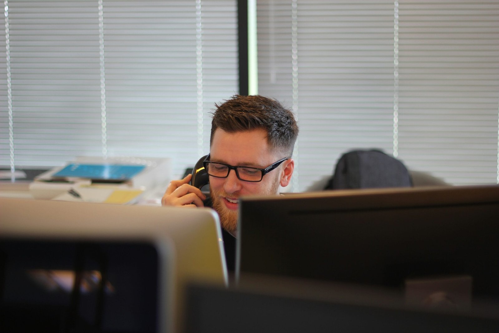 A man making a call on a cell phone behind his desk