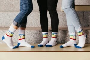 A group of feet repping cool socks with a "T" embroidered colorfully on them. Photo by Trnava University on Unsplash