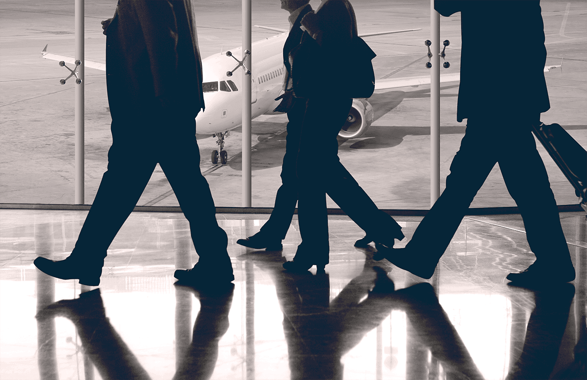 Men in black suits walking on a shiny airport floor in front of a plane. Photo by Rob Wilson on Unsplash