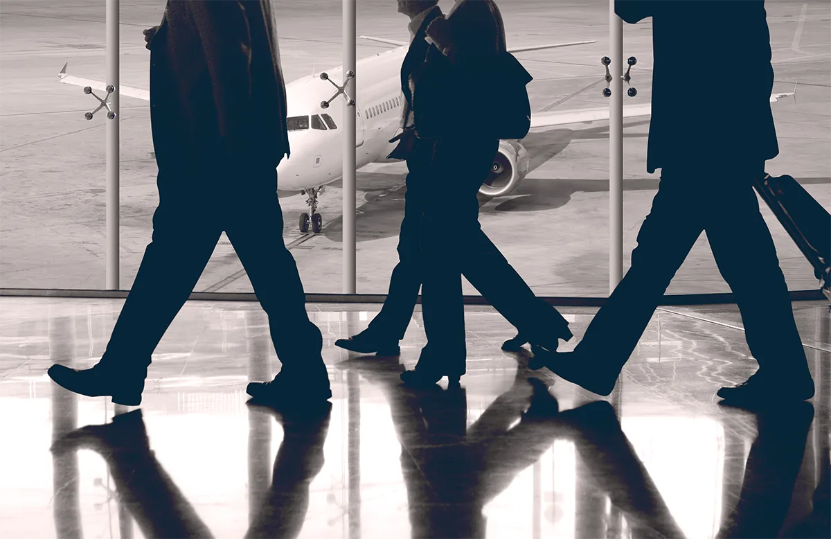 Men in black suits walking on a shiny airport floor in front of a plane. Photo by Rob Wilson on Unsplash