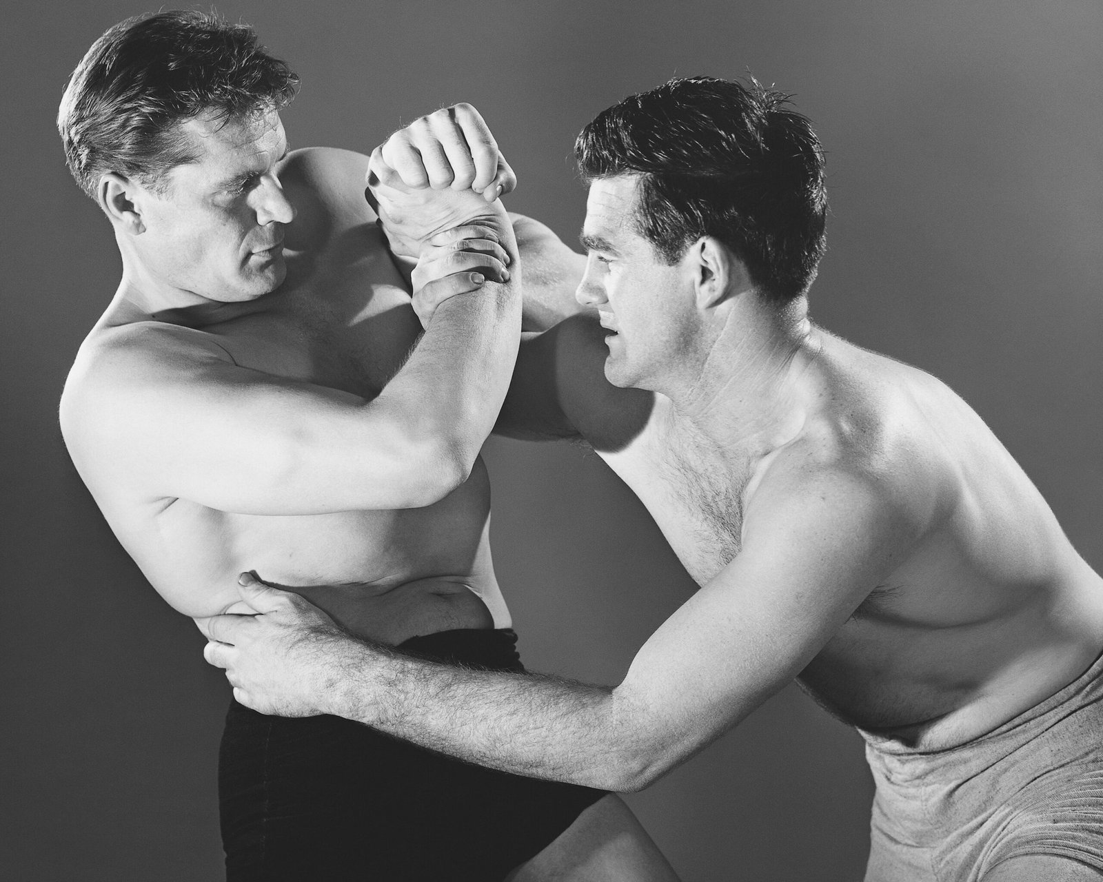 A black and white photo of a couple of men standing around fighting. Getty Images on Unsplash.