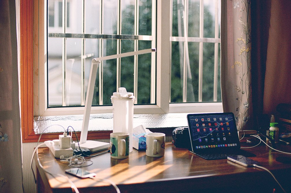 A desk setup with a laptop and a bright window. Photo credit Zhen Yao on Unsplash.