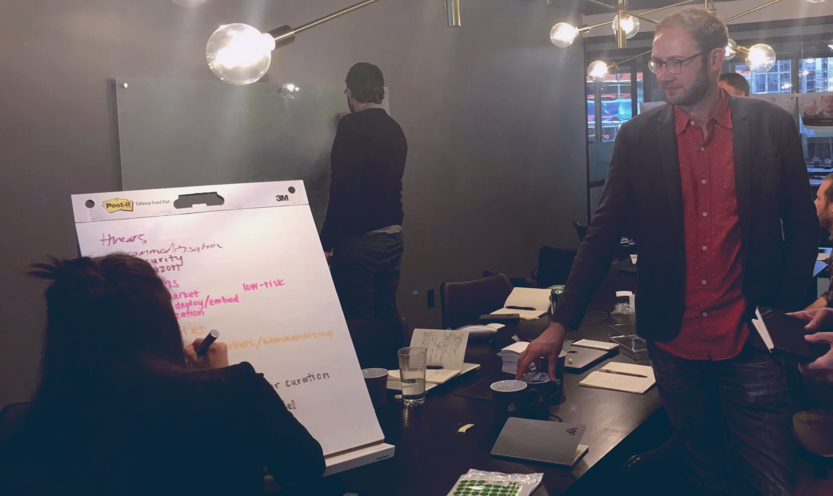 A group of colleagues in a conference room, where Jesse presents marketing strategy
